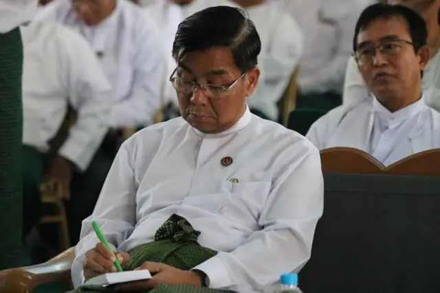 ကြံ့ခိုင်ရေးတံဆိပ်တပ်ထားတဲ့ ဦးပိုက်ထွေးကို အင်္ကျီအဖြူ၊ ပုဆိုးအစိမ်းနဲ့တွေ့ရစဥ်။