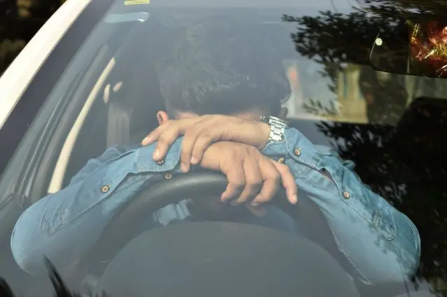 গাড়ির স্টিয়ারিং এ মাথা নিচু করে আছেন এক ব্যক্তি