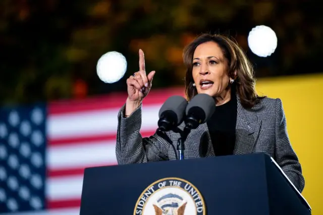 Kamala Harris discursandocassino da blazepalanque, com bandeira dos EUA ao fundo