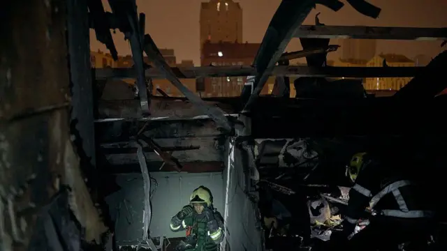 یک مأمور امداد و نجات با استفاده از چراغ قوه در حال جستجو در میان آوارهای برجای مانده از حملات موشکی تازه روسیه در کی‌یف 