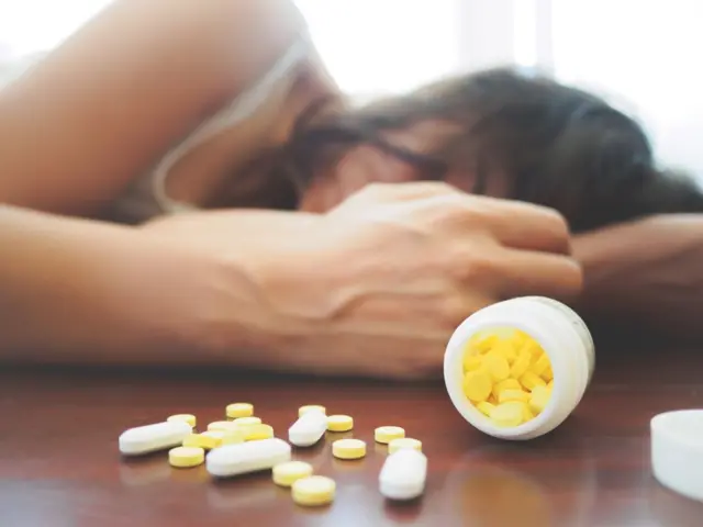 Seorang perempuan sedang tertidur dan di hadapannya terdapat banyak obat-obatan.