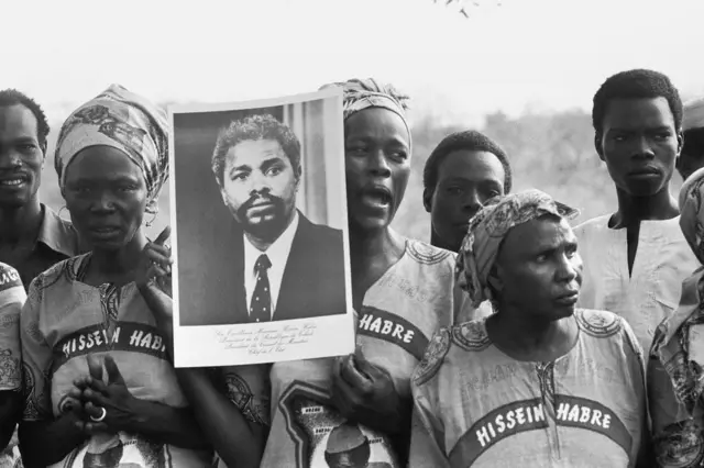 Un grupo de mujeres y hombres con una fotografía de Hissen Habré y con su nombre escrito en la ropa