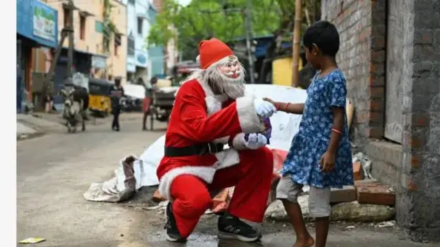 Ọkunrin kan wọ aṣọ Baba Keresimesi, n gbọwọ pẹlu ọmọde kan to n fun ni ṣokoleeti lọjọ Kẹrinlelogun, oṣu Kejila ọdun 2024.