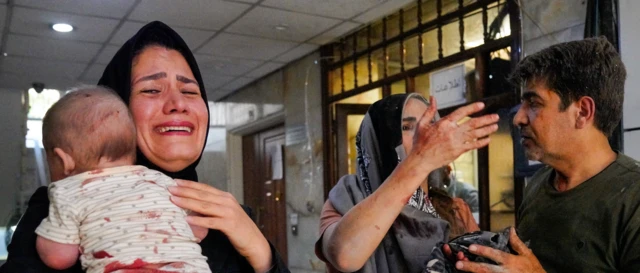 Tahran'ın bir meskun mahalinde İsrail saldırısı sonucu yaralanan bebeğini ağlayarak taşıyan İranlı bir anne.