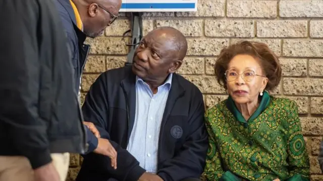 PrezidaCyril Ramaphosa (hagati) yicaye ariko aritegurira gutora kw'ishure ritoyi rya Hitekani mu gisagara ca Soweto, 29 ukwezi kwa Rusama 2024