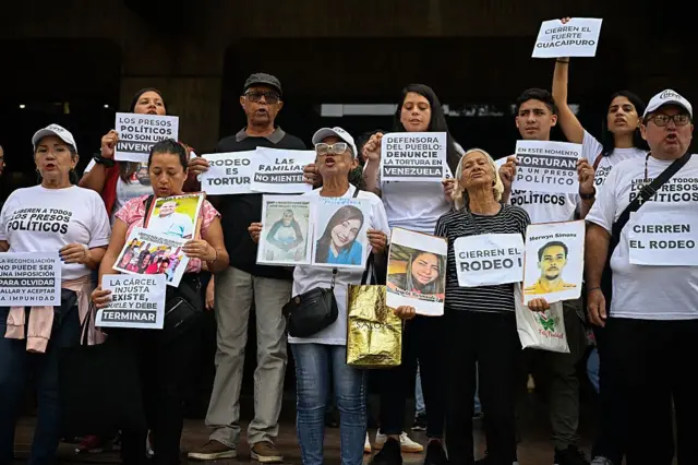 Familiares de presos políticos de pie y pegados en grupo. Llevan camisetas donde se lee "liberern a todos los presos políticos" y carteles donde pone "el rodeo es tortura", "Cierren el rodeo" y fotos de familiares.