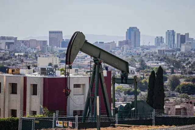 Pozo de petróleo y bombas de extracción en la ciudad de Signal Hill con la ciudad de Long Beach al fondo.