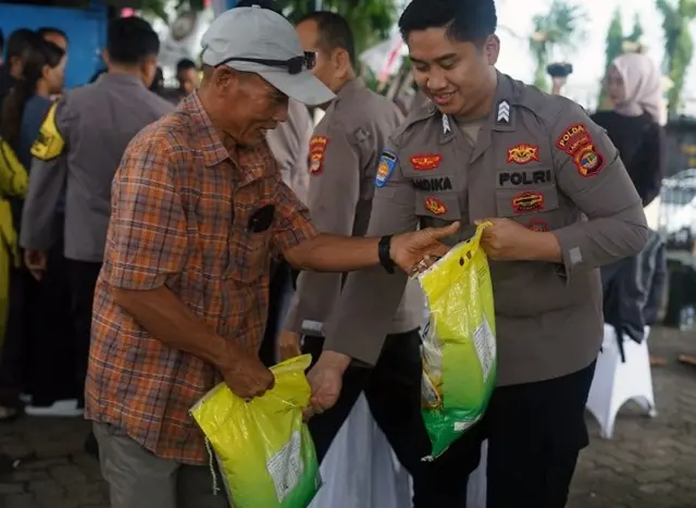 Anggota Kepolisian menyerahkan beras SPHP kepada pembeli saat peluncuran Gerakan Pangan Murah (GPM) serentak di Kantor Polda Lampung, Lampung, Kamis (14/8/2025). 