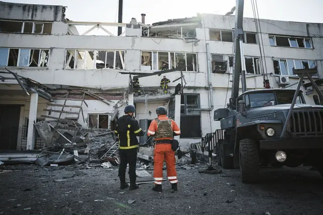 Bomberos viendo un edificio destruido por un ataque ruso