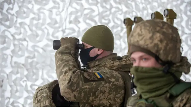 A Ukrainian Military Forces serviceman of the 92nd mechanised brigade uses binoculars live-fire exercises near the town of Chuguev, Kharkiv region on 10 February 2022