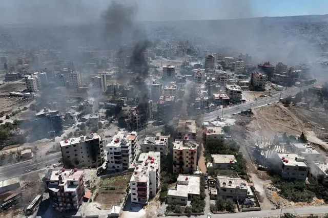 Süveyda'yı kuş bakışı görüyoruz. Kentten dumanlar yükseliyor.