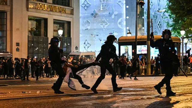 Dos policías antidisturbios cargan a un joven detenido