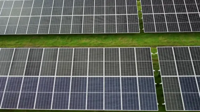Un campo lleno de paneles solares negros dispuestos en un patrón de cuadrícula.