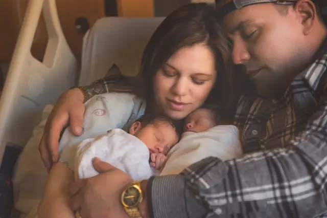 Orang tua memeluk kedua anaknya. 