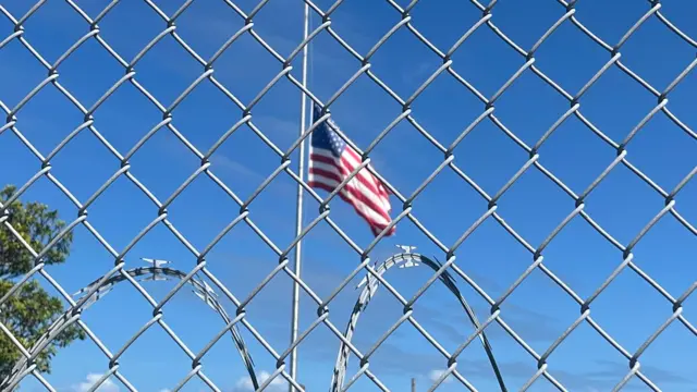 Uma bandeira americana tremulando no céu azul atrásbet367uma cercabet367arame farpado na Baíabet367Guantánamo