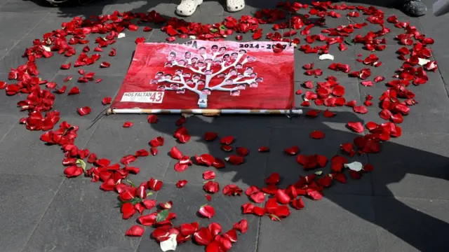 Pictures of the 43 missing students are displayed inside a heart shape made out of rose petals on the pavement in Mexico City