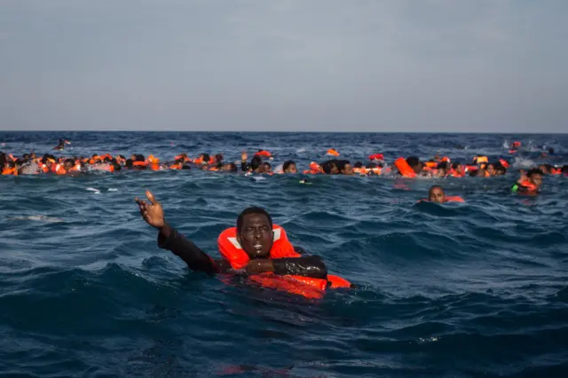 Migrantes no mar com coletes salva-vidas 