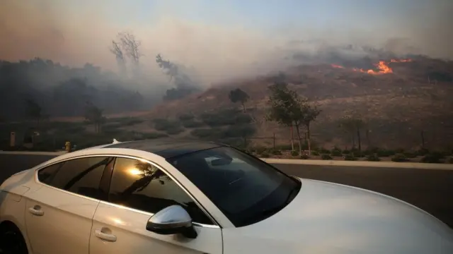 Машина на фоне охваченного огнем холма.