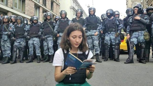 Olga Misik reads constitution as dozens of riot police stand behind her