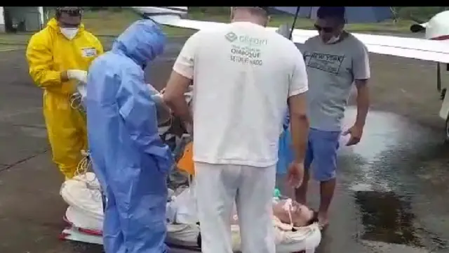 Paciente, equipe médica e homem segurando guarda chuva