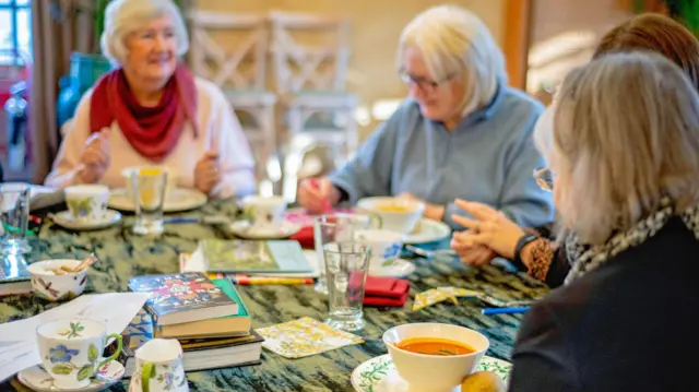 Жене седе за столом и једу чорбице