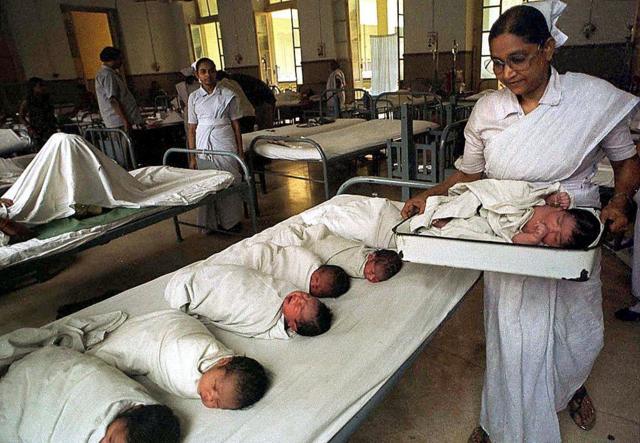 Uma enfermeira carrega um bebê em um hospital municipal em Calcutá
