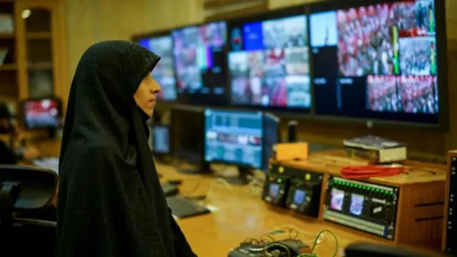 امرأة تتابع شاشات تلفزيونية في محطة إيرانية