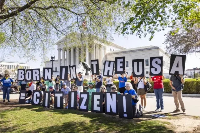 ギリシャ式の柱が並ぶ最高裁の白い建物の前、「BORN IN THE USA=CITIZEN!」と一文字ずつのプラカードを掲げて並んだ人たち。自由の女神の扮装をしている人もいる