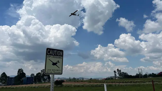 Un aeródromo abierto con nubes blancas en el cielo, con un dron volando sobre él.