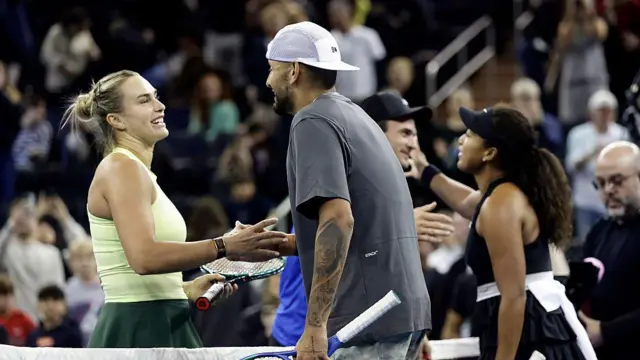 Australijczyk Nick Kyrgios poodaje rękę Białorusince Arynie Sabalence na korcie tenisowym. Sabalenka ma na sobie pistacjowy top, a Kyrgios szarą koszulkę i białą czapkę z daszkiem. Obaj trzymają rakiety tenisowe.