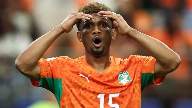 Amad Diallo, visible jusqu'à la poitrine, porte les mains à sa tête, incrédule, le regard fixe devant lui, la bouche grande ouverte en forme de O et l'air surpris.