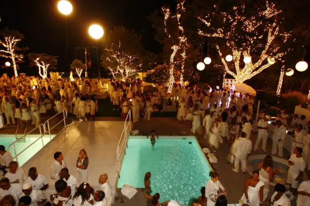 Uma Festa do Branco nos Hamptons, com pessoas vestidas de branco em volta de uma piscina