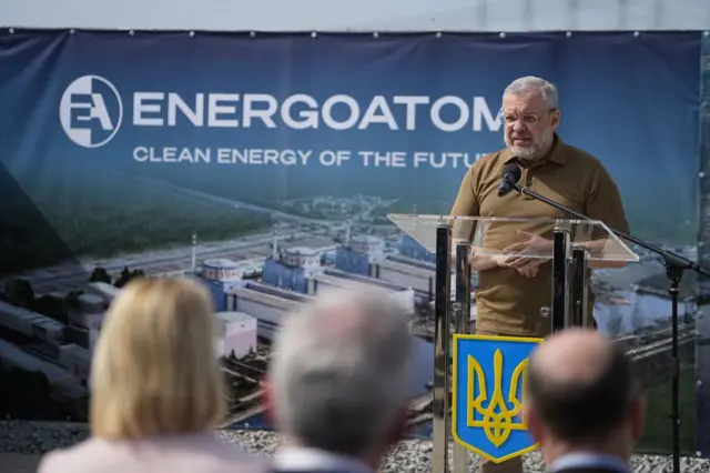 Галущенко виступає за трибуною з тризубом на тлі плаката з написом англійською Енергоатом - чиста енергія майбутнього