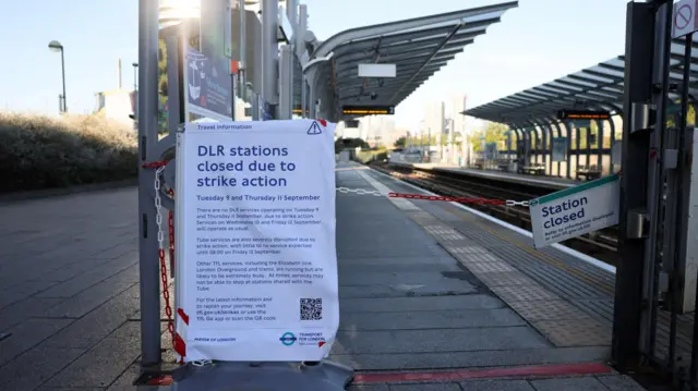 Пустаяа платформа закрытой на время забастовки станции одной из линий лондонского общественного транспорта. Вход на платформу перекрыт красно-белой цепочкой с табличкой "Станция закрыта". Рядом - плакат с объяснением, что это сделано из-за забастовки