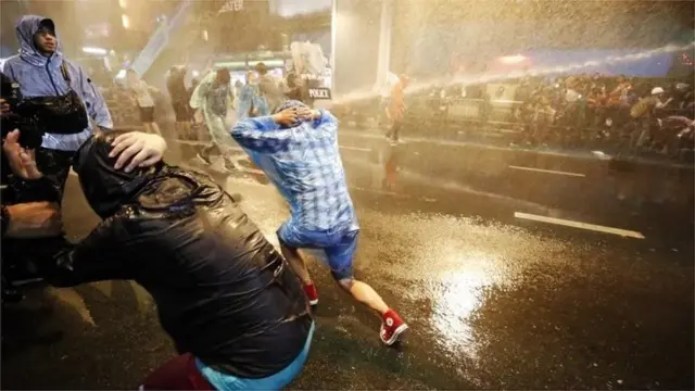 Pro-democracy protesters react as riot police fire water canons during an anti-government protest in Bangkok, Thailand, 16 October 2020