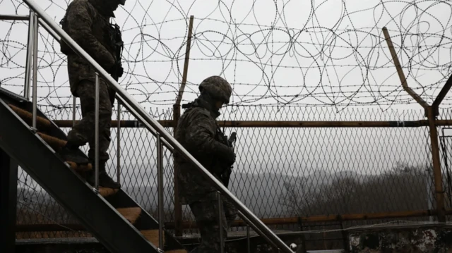 دو سرباز پشت حصارهای توری و سیم خاردار از پلههایی پایین میآیند