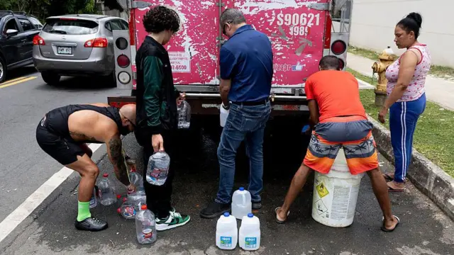 Un grupo de personas llenando recipientes de agua en un camión.
