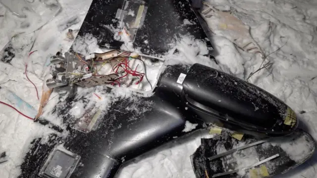 Поврежденный черный беспилотник в снегу. 