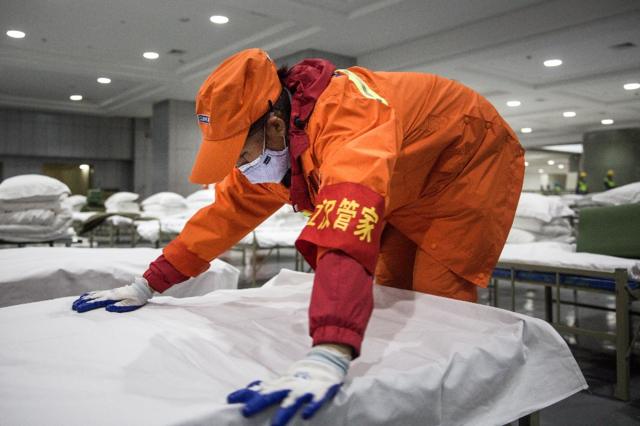 A cleaner checks beds at Wuhan International Conference and Exhibition Center (February 2020)