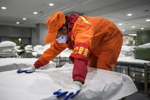 A cleaner checks beds at Wuhan International Conference and Exhibition Center (February 2020)
