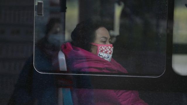 ผู้หญิงสวมหน้ากาก ขณะนั่งอยู่บนรถประจำทางใกล้กับตลาดขายส่งอาหารทะเลหัวหนานในจีน