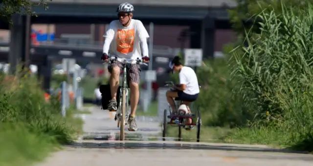 Mike Berglund mengendarai sepedanya saat gelombang panas naik dari trotoar dalam jalur pendakian dan bersepeda di Heights Selasa, 2 Agustus 2011, di Houston.