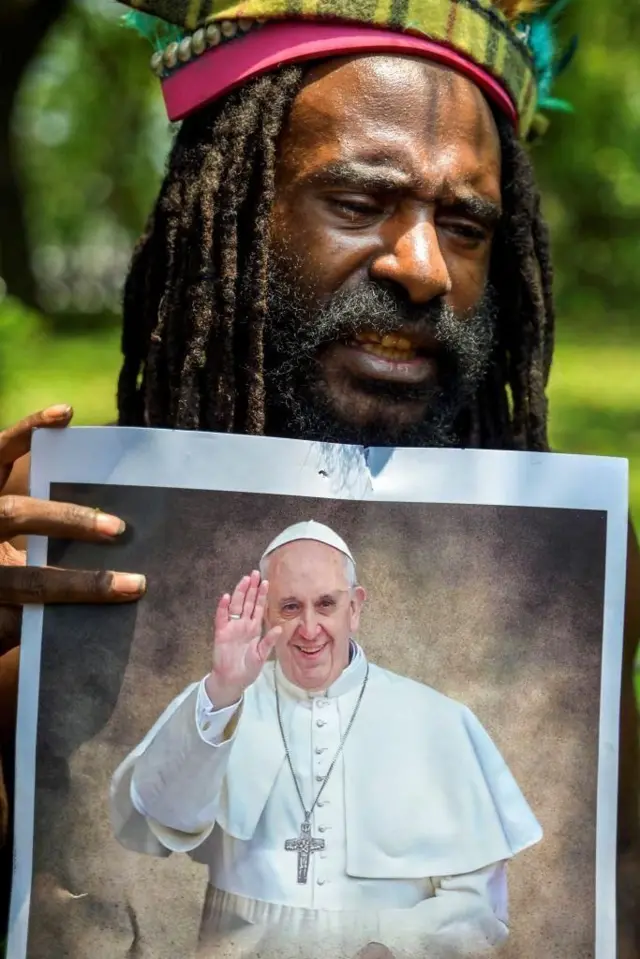 Seorang pria Papua memegang foto Paus Fransiskus di depan Kedutaan Vatikan di Jakarta