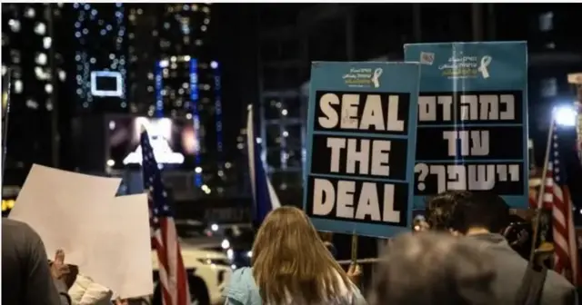 Люди на протесті з плакатами з закликом укласти угоду і повернути заручників 