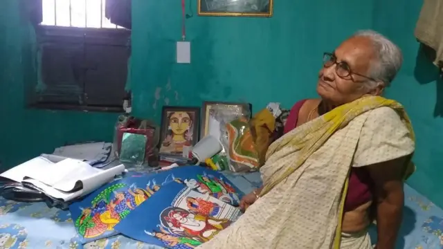 কৃষ্ণনগরে তার বাড়ির খাটে বসে শিল্পী রেবা পাল। 