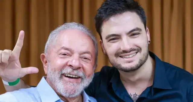 Felipe Neto faz a letra L com a mão ao lado de Lula