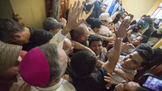 Silvio Báez rodeado de una multitud en la que hay hombres con pasamontañas.