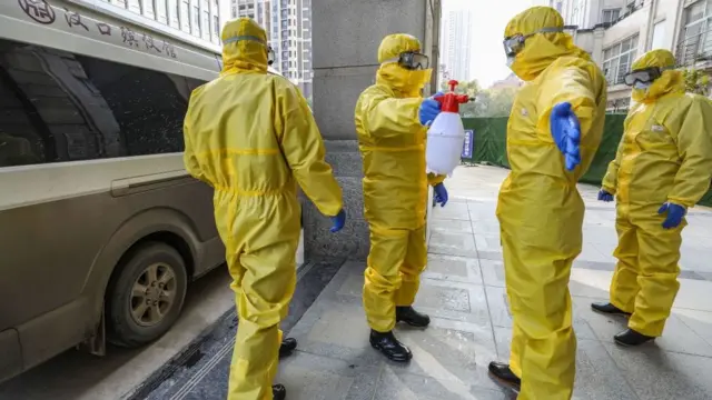 Сотрудники похоронного бюро в защитных костюмах