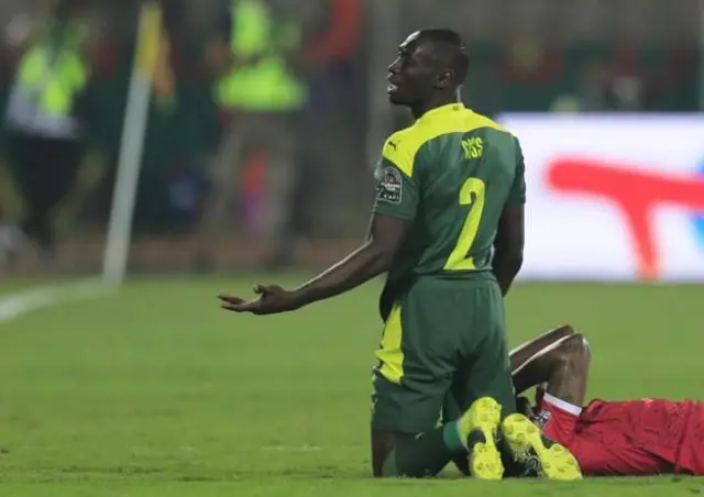 Equatorial Guinea defender dey ground afta e catch elbow for face from Senegal player