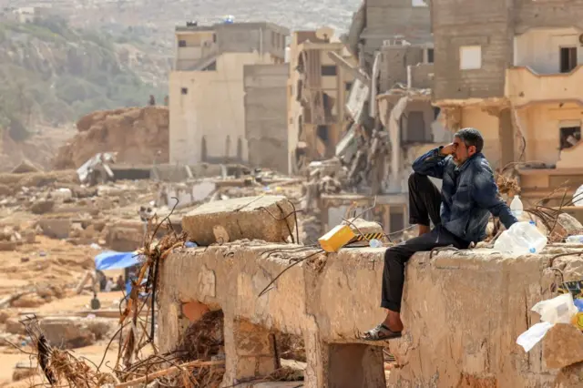 A man reacts as he sits on the rubble of a destroyed building in Libya's eastern city of Derna on 18 September 2023 following deadly flash floods